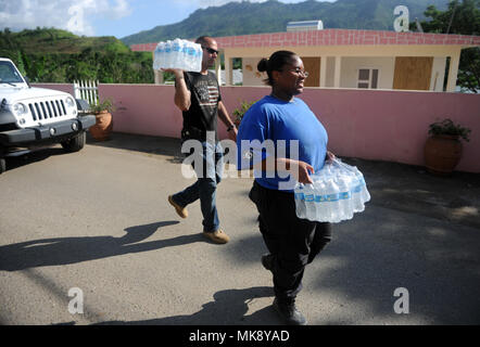 VILLALBA, Puerto Rico - FEMA Spitzenkapazität Kraft Mitglied Edys Batista und einem FEMA Corps worker Tragetaschen von Wasser zu den Häusern in einem kleinen Puerto Rican Mountain Community. Arbeiten in Abstimmung mit den örtlichen Regierungsbeamten, FEMA Arbeitnehmer mehr als 200 Kästen Nahrung und 300 Fälle von Wasser für die Bewohner der Caonillas Abajo Nachbarschaft am 07.11.25.. Stockfoto