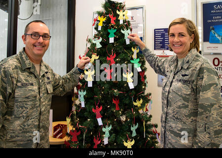 Chief Master Sgt. Jarrod Sebastian, Links, 23d Wing command Chief und Oberst Jennifer Kurz, 23d Wing Commander, posieren für ein Foto, November 27, 2017, bei Moody Air Force Base, Ga. Jedes Jahr werden Mitglieder der Gemeinschaft Verzierungen von den Bäumen an der Basis Exchange und der Freiheit 1 Fitnesscenter mit Beschreibung des Kindes und Ihre gewünschte Geschenk befindet, nach oben ziehen, und kauf das Geschenk anonym gegeben werden. (U.S. Air Force Foto von Airman 1st Class Erick Requadt) Stockfoto