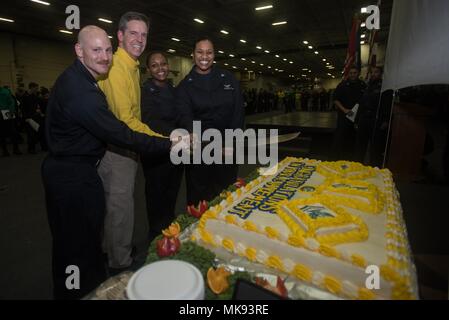 171127-N-CL 027-695 GEWÄSSER SÜDLICH VON JAPAN (Nov. 27, 2017) Kapitän Buzz Donnelly, kommandierender Offizier der Marine vorwärts - bereitgestellt Flugzeugträger USS Ronald Reagan (CVN 76), Mitte-links, schneidet den Kuchen mit Neu frocking frocked Segler während einer Zeremonie im Hangar Bay. Ronald Reagan, das Flaggschiff der Carrier Strike Group 5, bietet eine Bekämpfung bereit, Kraft, schützt und verteidigt die kollektive maritime Interessen seiner Verbündeten und Partnern in der Indo-Asia-Pazifik-Region. (U.S. Marine Foto von Mass Communication Specialist 2. Klasse Janweb B. Lagazo) Stockfoto