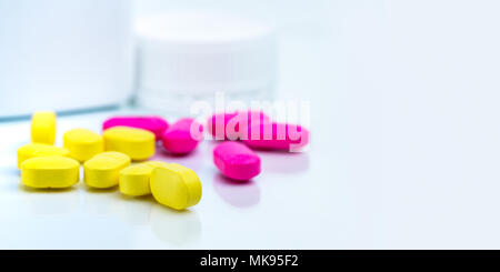 Selektiver Fokus auf Gelb eiförmig rechteckig Tablette Pillen auf unscharfen Hintergrund rosa Tablette Pillen und Medizin Flasche mit kopieren. Apotheke oder d Stockfoto