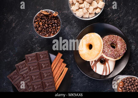 Blick von oben auf die Schokolade Tabletten, Donuts, brauner Zucker mit Erdnüssen in Schokolade und Kaffee Bohnen Stockfoto