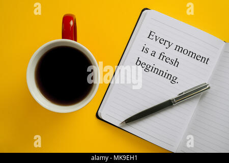 Jeder Augenblick ist ein neuer Anfang. Inspirational Anführungsstrich auf Notebook mit einem Becher Kaffee. Stockfoto