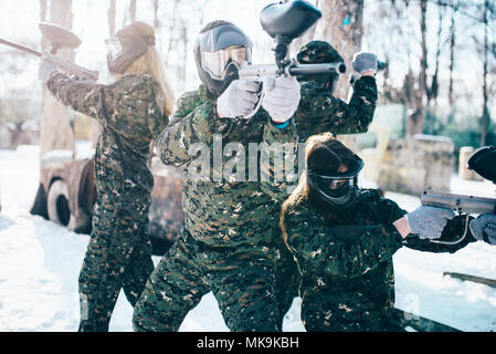 Paintball Spieler in Uniform und Masken wirft mit Marker Gewehren in den Händen nach dem Winter Wald Kampf. Extreme Sport Spiel Stockfoto
