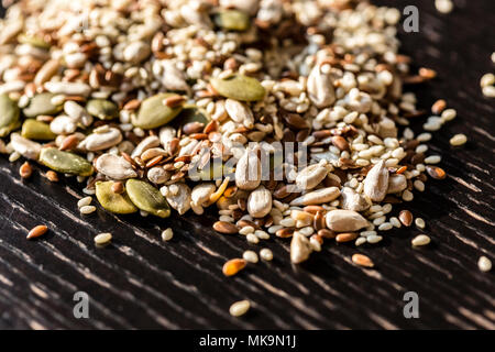 Trockenen Samen Kürbis, Sesam, Sonnenblumen, Flachs für gesunde Ernährung auf dem hölzernen schwarz Tabelle gemischt. Stockfoto