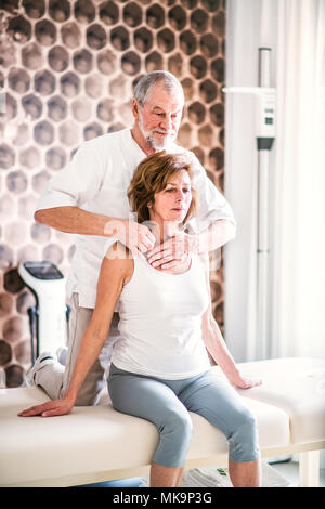 Leitender Physiotherapeut arbeitet mit einem weiblichen Patienten. Stockfoto