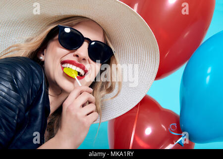 Schöne Rocker Girl in Lederjacke und Sonnenbrille mit Herzförmigen lolipop und herzförmige Luftballons. Attraktive cool junge Frau Mode portra Stockfoto