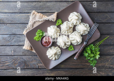 Georgische Knödel Khinkali mit Fleisch, Gemüse und Tomaten würziger Sauce Satsebeli, Ansicht von oben Stockfoto