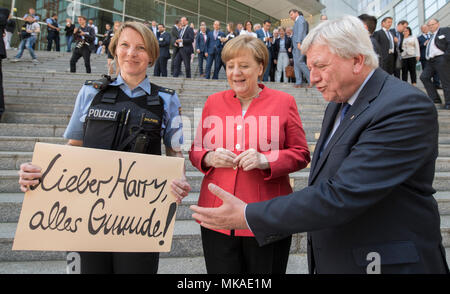 Frankfurt am Main, Deutschland. 7. Mai, 2018. Die deutsche Bundeskanzlerin Angela Merkel (CDU, C) und Volker Bouffier, der hessische Ministerpraesident, Konferenz Polizeioffizier Susanne Rohlfing, der mit einem Schild mit dem Text "Lieber Harry, beste Wünsche!", nachdem die CDU/CSU-Fraktion Chairpeople Conference in der Commerzbank Tower. Die Offiziere der 1 Revier Abschied mit dem Zeichen zu einem Kollegen, der in den Ruhestand Nach 40 Jahren ist. Foto: Boris Roessler/dpa Quelle: dpa Picture alliance/Alamy leben Nachrichten Stockfoto