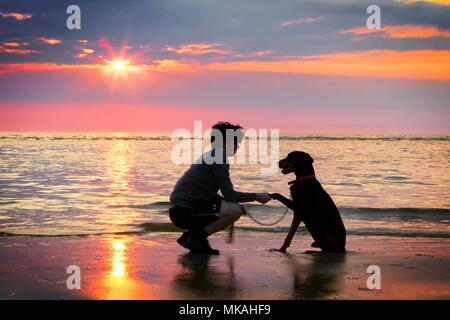 Ainsdale Strand, Southport, Merseyside. 7. Mai 2018. UK Wetter. Sam Elias [MR] steht mit seinem besten Freund 'Charlie' der Dobermann und Uhren einen schönen Sonnenuntergang in den Horizont nach dem heißesten Tag des Jahres so weit am Strand in Southport, Merseyside. Credit: cernan Elias/Alamy leben Nachrichten Stockfoto