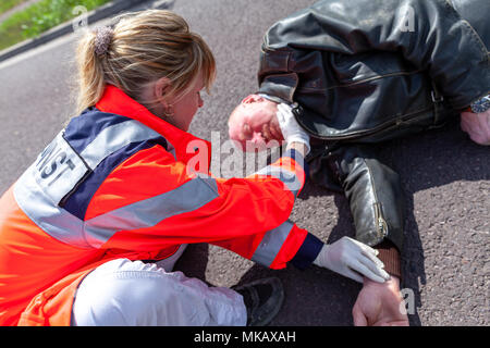 Ein deutscher Sanitäter prüfen Blutdruck auf eine verletzte Biker. Rettungsdienst ist das deutsche Wort für Krankenwagen. Stockfoto