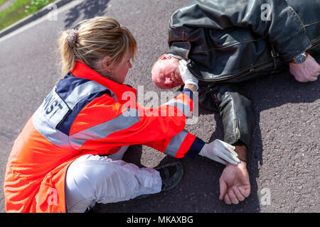 Ein deutscher Sanitäter prüfen Blutdruck auf eine verletzte Biker. Rettungsdienst ist das deutsche Wort für Krankenwagen. Stockfoto