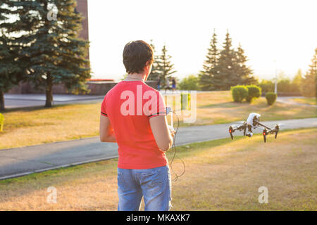 Mann die Drohne fliegt oder schwebt per Fernbedienung in der Natur. Stockfoto