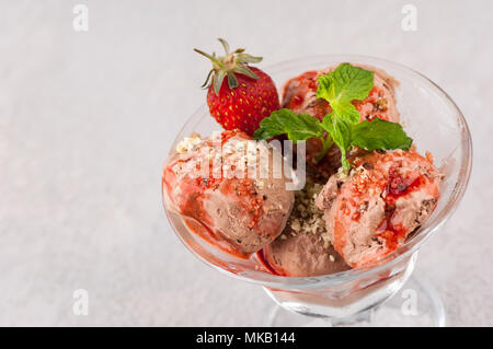 Eis mit Erdbeeren in einem Glas Vase auf einem leicht gerippte Oberfläche. close-up. Der Blick von oben Stockfoto