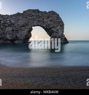 Am frühen Morgen Licht scheint durch die natürlichen Kalkstein arch at Durdle Door auf Englands Jurassic Coast. Stockfoto