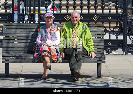 Ältere Paare in bunte Kleidung sitzen auf einer Bank in der Sonne gekleidet. Stockfoto