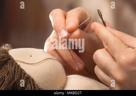 Hände von Frau Haar Nähen auf die Waldorf Puppe, Nahaufnahme Stockfoto