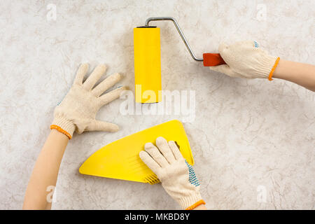 Hände mit Spachtel und Walze Glättung Tapeten an der Wand während der Reparatur Stockfoto