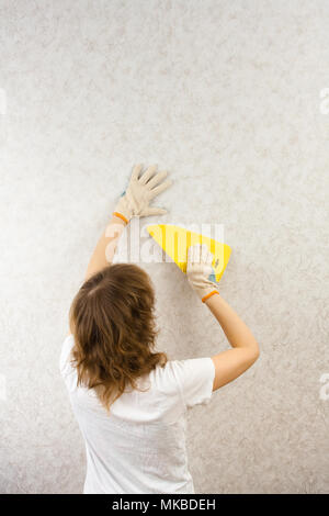 Frau Glättung Tapete mit Spachtel an der Wand Stockfoto