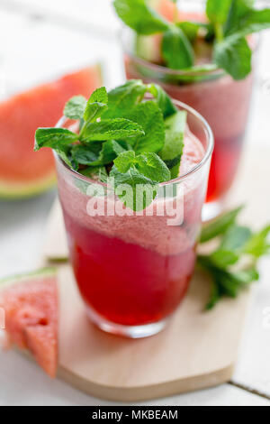 Closeup Schuß aus Glas mit Kühlung Wassermelone Limonade gefüllt und gekrönt mit grüner Frische Blätter. Stockfoto