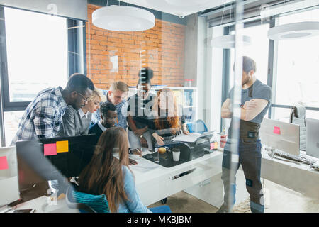 Junge Aktive büroangestellten haben um einen Tisch versammelt. Forschung zu tun. Stockfoto