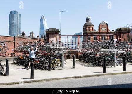 Waterloo Station, London UK. 2018. Zwei Parkplätze für Kunden ihre Zyklen zu parken. Eine männliche Kunden parken sein Fahrrad Stockfoto