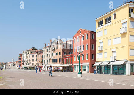 Farbenfrohe Gebäude auf Riva dei Sette Martiri, Castello, Venedig, Venetien, Italien mit Menschen zu Fuß entlang der Promenade genießen Sie die Frühlingssonne Stockfoto