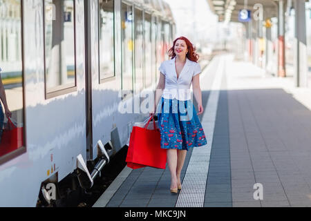 Schöne Frau geht mit Tüten auf der Plattform eines Bahnhof Stockfoto