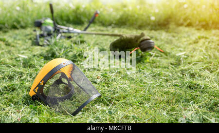 String Trimmer und schützende Maske auf gemähten Gras, Gras auf dem Hintergrund, Banner 16x9 Format Stockfoto