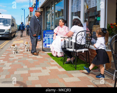 Ein älterer Yorkshire mann Witz zwei kleine Hunde hält mit zwei Damen und ein Mädchen bei der äußeren Tabelle der ein Cafe in Redcar North Yorkshire zu chatten Stockfoto
