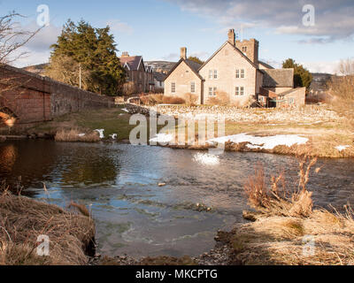 Bampton, England, UK - 29. März 2013: Die Sonne scheint auf die Häuser von Bampton Grange Village, neben dem Fluss Lowther, an einem Wintertag in Cumbria. Stockfoto