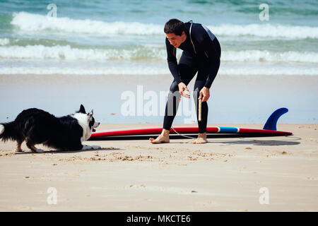 Surfer spielen mit einem Hund begore ins Wasser Stockfoto