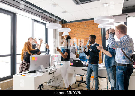 Junge mixed-race Business Group hält die Arme angehoben und Spaß drinnen Stockfoto