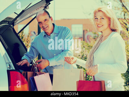 Älterer Mann und Frau setzen Taschen mit Einkäufe im Kofferraum eines Autos Stockfoto