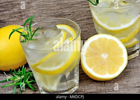 Detox Wasser mit in Scheiben geschnittenen Zitronen und Rosmarin in die Gläser auf dem Tisch. Erfrischende kalte Sommer trinken Stockfoto
