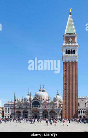 Touristen Sightseeing in Piazza San Marco (Markusplatz), Venedig, Venetien, Italien vor St Marks Kathedrale (Basilca San Marco) und der Campanile Stockfoto