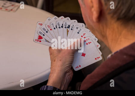 ASCIANO, Toskana, Italien - 25 April 2018: Asciano mit Schluchten, Farmen in einer rauen Landschaft, unbekannter Mann spielt Karten Stockfoto