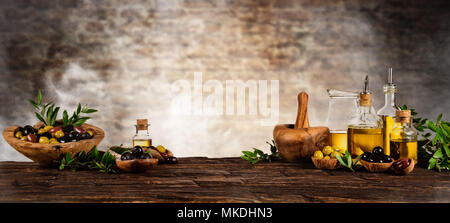 Frisch geerntete Oliven Beeren in Holz Schalen und kaltgepresstes Öl in Glasflaschen. Stillleben der Zubereitung von Speisen serviert auf alten Holzdielen. Kostenlose spac Stockfoto