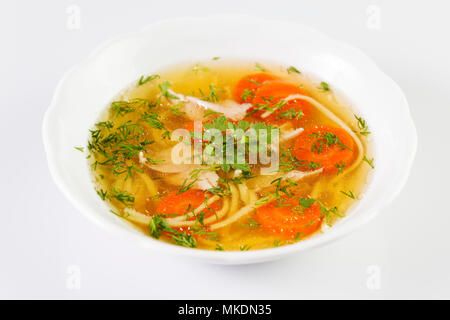 Huhn Suppe oder Brühe mit Nudeln, Hähnchen Fleisch, Karotten Scheiben und Kräutern in weiße Schüssel. Stockfoto