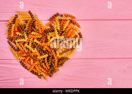 Herz aus bunten fusilli Makkaroni. Form des Herzens aus bunten spiralförmige Pasta und Platz für Text. Valentines urlaub Hintergrund. Gesunde fo Stockfoto
