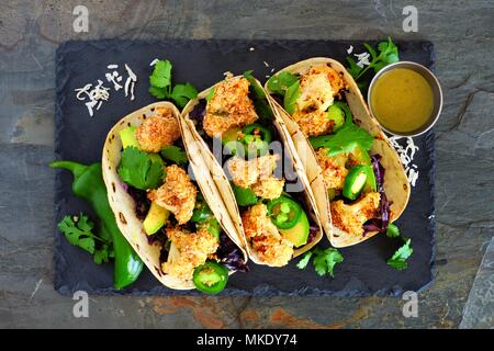 Roasted Coconut Blumenkohl Tacos. Gesunde, vegane Mahlzeit. Oben Blick auf dunklem Schiefer Hintergrund. Stockfoto