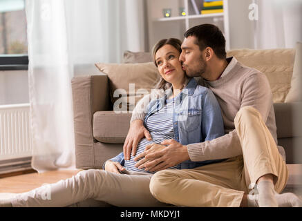 Mann küssen und umarmen schwangere Frau zu Hause Stockfoto