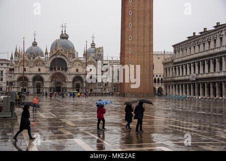 Touristen Kreuzung St. Markusplatz mit Sonnenschirmen im Regen, Venedig Stockfoto