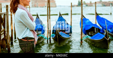 Eine Frau steht, Träumen der Vergangenheit hören auf den Klang des Wassers gegen die festgemachten Gondeln Läppen. Stockfoto