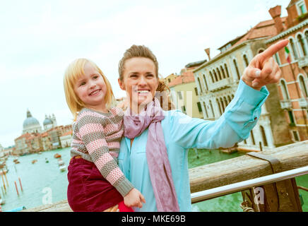 Baby Mädchen und Mutter deutete beim stehen auf der Brücke mit Blick auf Canale Grande in Venedig, Italien Stockfoto