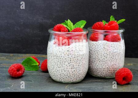 Gesunde Himbeere chia Pudding in Gläsern. Szene mit einem dunklen Stein Hintergrund. Stockfoto