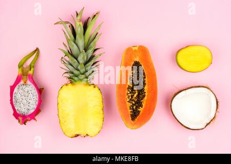 Tropische Früchte flach mit Ananas, Drachenfrucht, Papaya, Mango, und Kokosnuss auf einem Pastell rosa Hintergrund Stockfoto