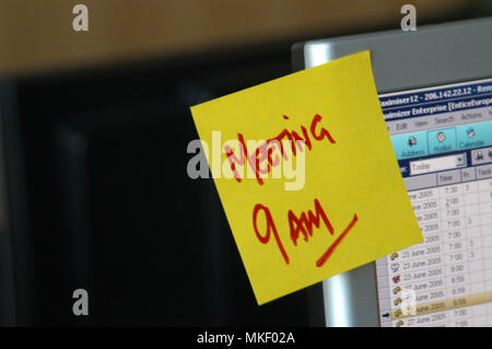 Meeting um 9 Uhr auf einem Klebezettel als Erinnerung am Computer im Büro Stockfoto