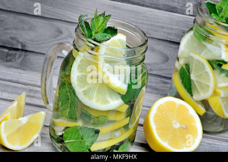 Detox Wasser mit Zitrone und Minze in einem Gläschen auf grau Holz Tisch Stockfoto