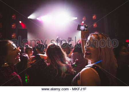 Portrait begeisterte Frau mit Kamera Handy in Menge, Nachtclub videoing DJ auf der Bühne
