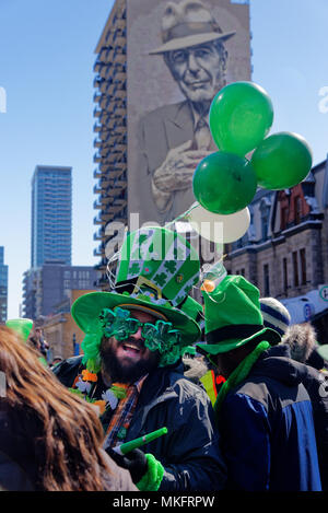 Eine lachende Mann, der Shamrock geformte Sonnenbrille am Montreal St. Patricks Day Parade, mit den grossen Portrait von Leonard Cohen hinter Stockfoto